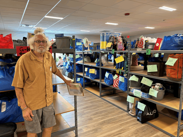 "Maine Needs" volunteer Lee Cooper stands near bags of filled orders, ready for providers to pick up for clients