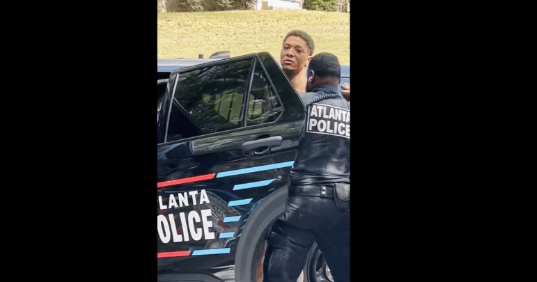 Groves, seen being put into the back of a police car in a video of his arrest by Atlanta police.