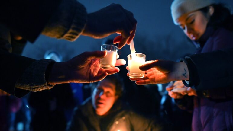 People light candles at the beginning of a vigil for those injured or killed during the Saturday shooting on the campus of Brown University.