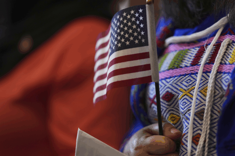 A woman clutches a U.S. flag as she and applicants from 20 countries prepare to take an oath of citizenship in commemoration of Independence Day during a naturalization ceremony in San Antonio in July 2025.
