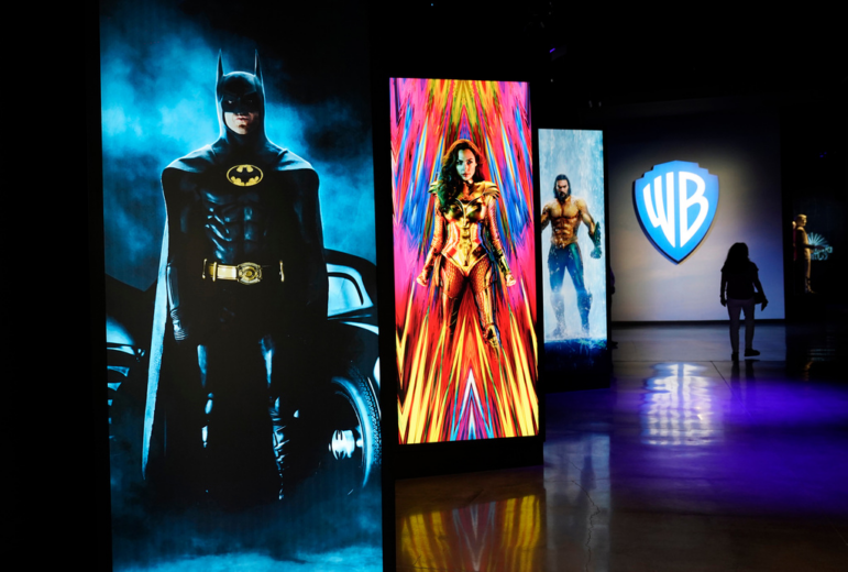 A visitor walks past portraits of DC Comics superheroes as she enters the "Action and Magic Made Here" interactive experience at the Warner Bros. Studio Tour Hollywood media preview on June 24, 2021, in Burbank, Calif.