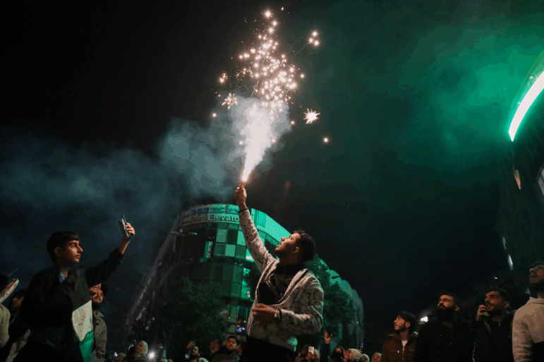 A man lights a flare during celebrations marking the first anniversary of the ousting of the Bashar al-Assad regime in Clock Square, Homs, western Syria, Monday.