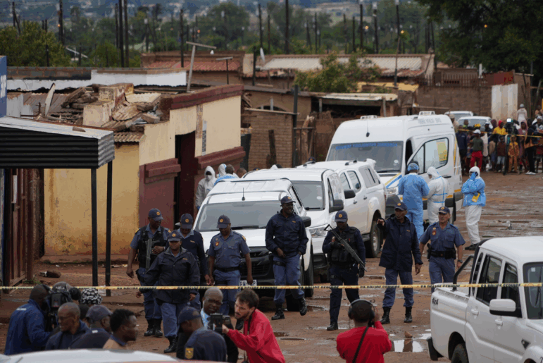 South African police gather at the scene of a mass shooting where gunmen killed nine and injured at least 10 in a pub in Bekkersdal, South Africa, Sunday, Dec. 21, 2025.