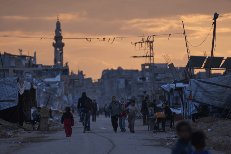 Palestinian youth walk along a tent camp for displaced people as the sun sets in Nuseirat, central Gaza Strip, Friday, Dec. 26, 2025.
