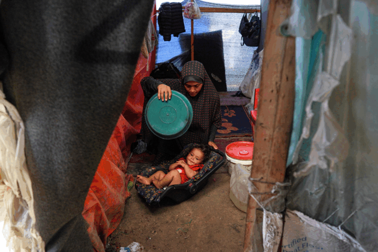 A displaced Palestinian woman uses a plastic plate to fan a baby during a heatwave in Deir al-Balah, in the central Gaza Strip, on June 11, 2024, amid the ongoing conflict between Israel and the Palestinian Hamas militant group.