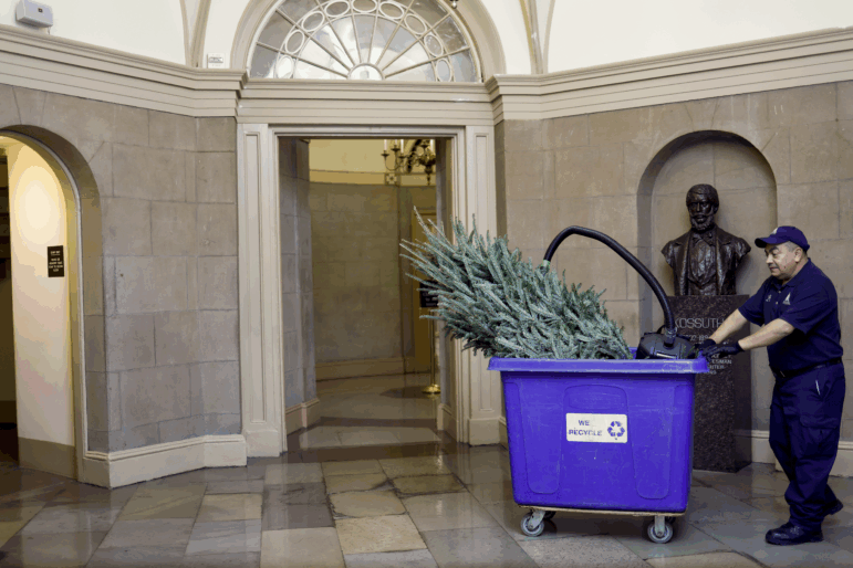 A staff member with the Architect of the Capitol carries a Christmas tree in a recycling bin through the U.S. Capitol in Washington, Dec. 23, 2022.
