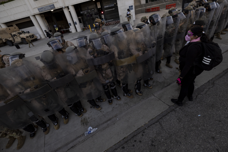 U.S. Marines and National Guard troops patrol the entrance of the Metropolitan Detention Center in Los Angeles as demonstrators gather on July 4, 2025.