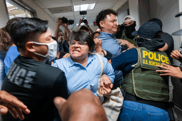 A Paraguayan woman whose relative was detained by federal agents scuffles with officers in the halls of immigration court at the Jacob K. Javitz Federal Building on in New York City in July 2025.