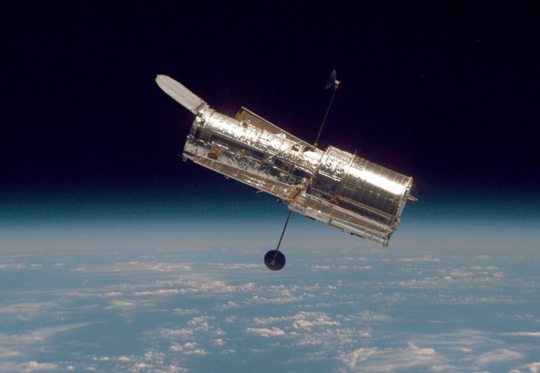 The Hubble Space Telescope drifts through space in a picture taken from the Space Shuttle Discovery in 1997. A study finds reflections cast by satellites could ruin images taken by telescopes.