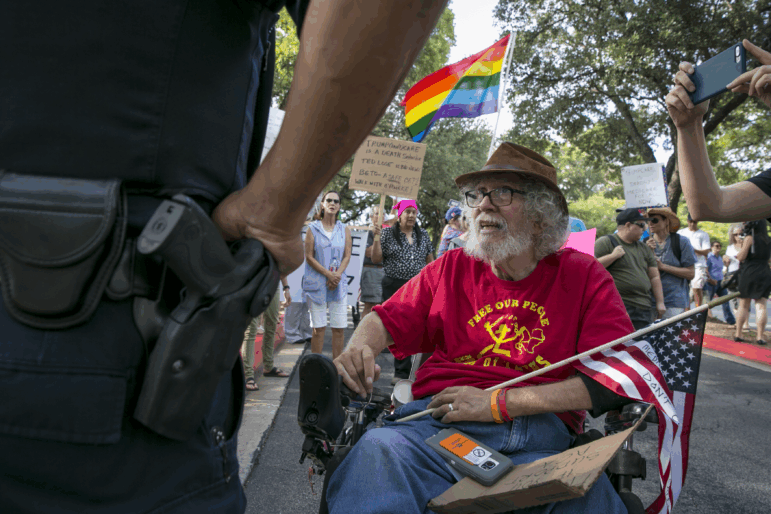 Bob Kafka, a disabled Vietnam veteran, talks with an Austin Police Officer as he and others try to enter a hotel property.