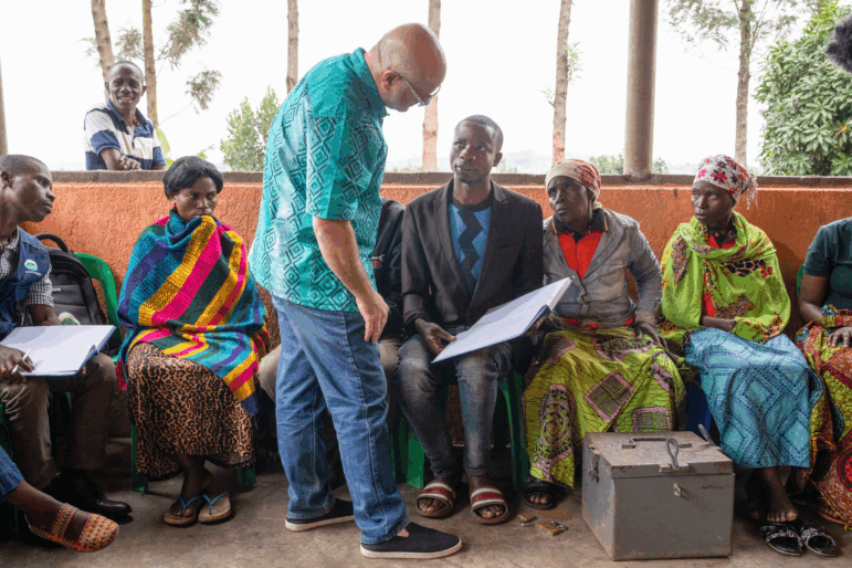 Dean Karlan (in blue shirt) meets with a group of refugees in southwest Uganda to hear about their experience with a program that offers loans to help them "graduate" from poverty.
