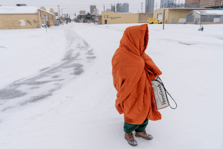Shannon White, who has been homeless for 30 years, uses a blanket to stay warm while walking to a day shelter during Winter Storm Fern in Oklahoma City, Oklahoma January 24, 2026.