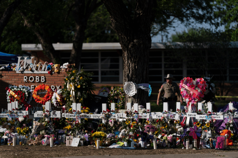 Flowers and candles are placed around crosses to honor the victims killed in a school shooting, May 28, 2022, outside Robb Elementary School in Uvalde, Texas.