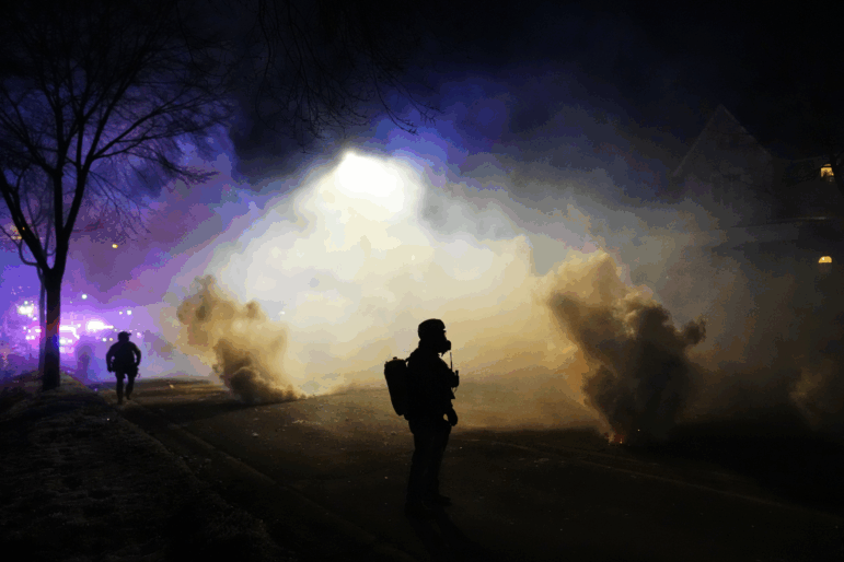 Law enforcement officers stand amid tear gas at the scene of a shooting Wednesday in Minneapolis.