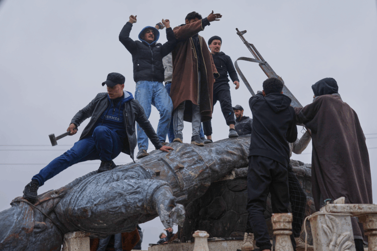 Residents topple a statue of a female Kurdish fighter after the takeover of the town by Syrian government forces from U.S.-backed Syrian Democratic Forces (SDF), in Tabqa, eastern Syria, on Sunday.