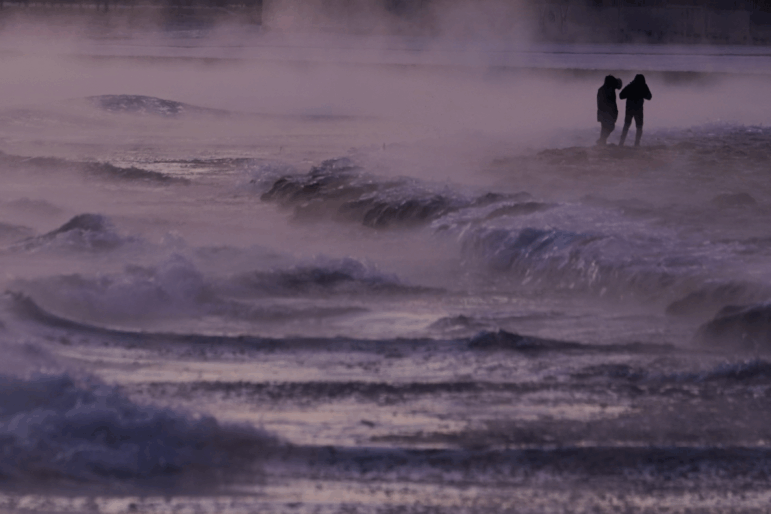 People walk on an ice covered beach along the shore of Lake Michigan, Friday, Jan. 23, 2026, in Chicago.