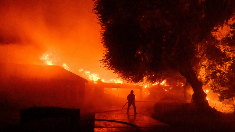 A firefighter works as homes burn during the Eaton fire in the Altadena area of Los Angeles County, Calif., on Jan. 7, 2025.