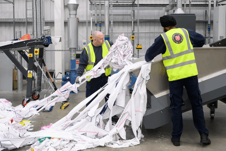 Workers load unwanted polyester textiles into the Project Re:Claim system, the first commercial-scale polyester recycling plant of its kind, on February 28, 2025 in Kettering, England.