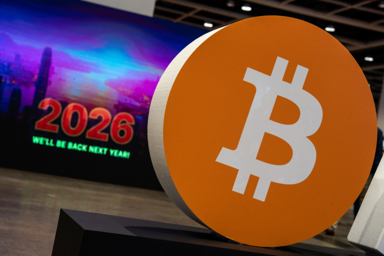 A bitcoin logo is displayed at a conference in Hong Kong on Aug. 28, 2025. Bitcoin and other cryptocurrencies soared this year — until crashing in October.