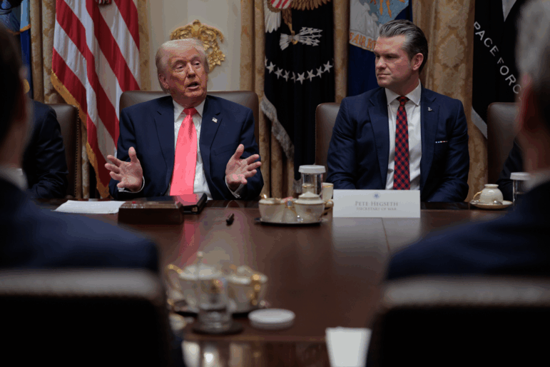 President Trump speaks as U.S. Secretary of War Pete Hegseth looks on during a meeting of his Cabinet in the Cabinet Room of the White House in December 2025.