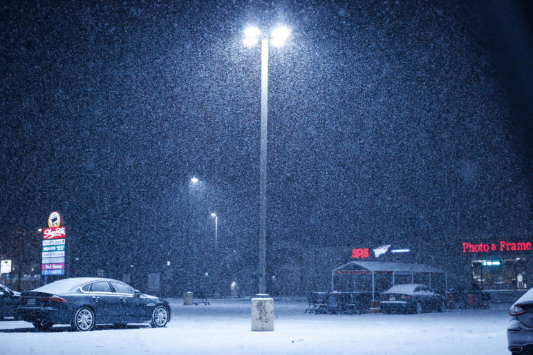 Snow falls on an empty parking lot outside a supermarket in December in Northvale, N.J.
