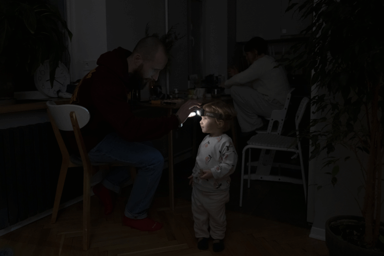 Local resident Stas helps his two-year-old daughter use a headlight