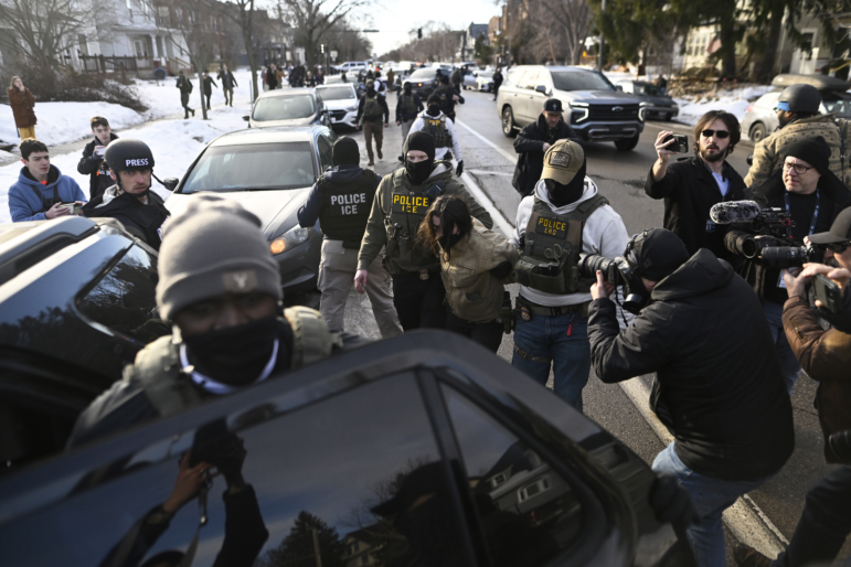 An observer is detained by ICE agents after they arrested two people from a residence in Minneapolis on Jan. 13.