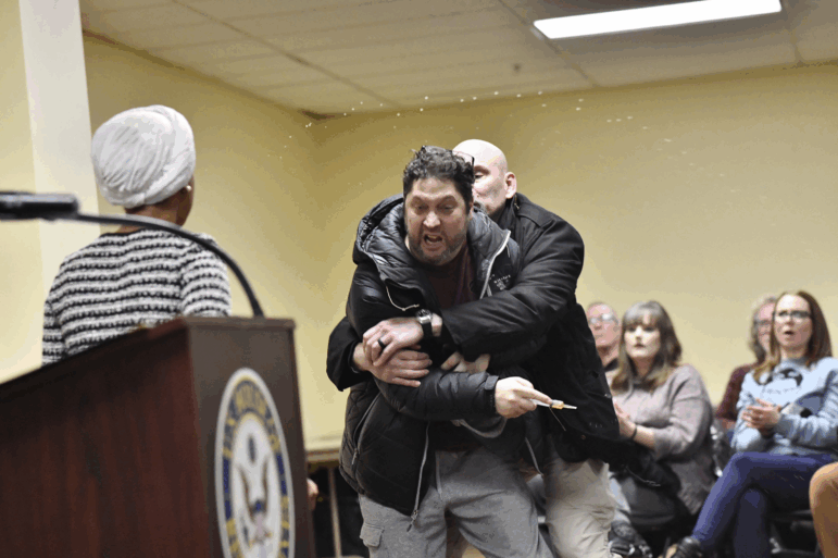 A man is tackled after spraying an unknown substance at US Representative Ilhan Omar (D-MN) (L) during a town hall she was hosting in Minneapolis, Minnesota, on January 27, 2026. (Photo by Octavio JONES / AFP via Getty Images)