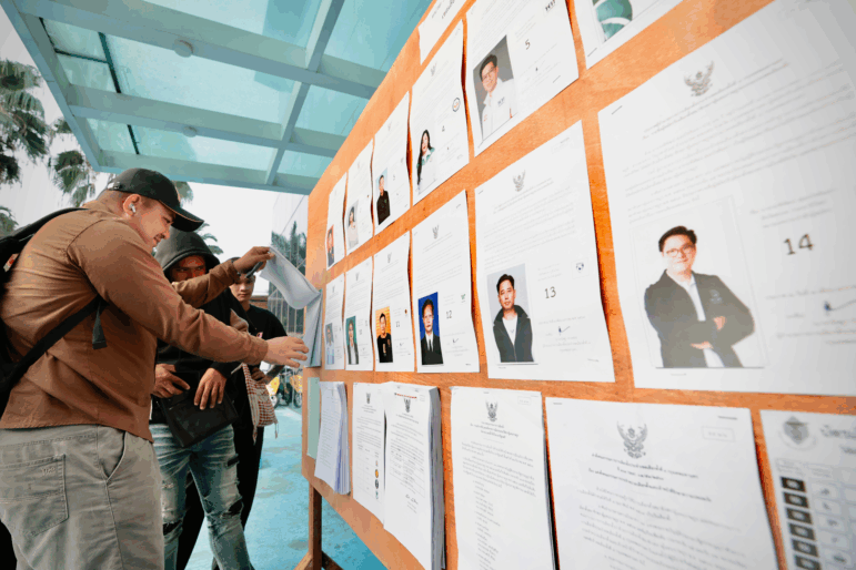 Voters look at candidates listed on a display board before entering a voting station for the general election in Bangkok, on Sunday, Feb. 8, 2026.