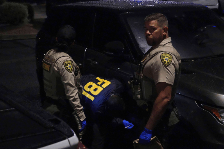 Law enforcement from the Pima County Sheriff's Department and the FBI work on a Range Rover in a Culver’s parking lot in Tucson, Ariz., early Saturday.