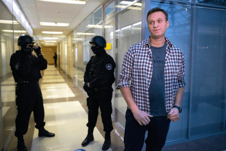 FILE - Russian opposition leader Alexei Navalny speaks to the media in front of security officers standing guard at the Foundation for Fighting Corruption office in Moscow, Russia, Thursday, Dec. 26, 2019.