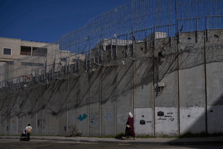 Palestinians walk along the separation barrier between the West Bank and east Jerusalem neighborhood of Beit Hanina, Sunday Feb. 15, 2026.