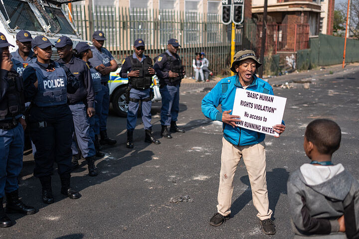 A resident holds a placard as he shouts slogans during a protest over water cuts in Johannesburg.