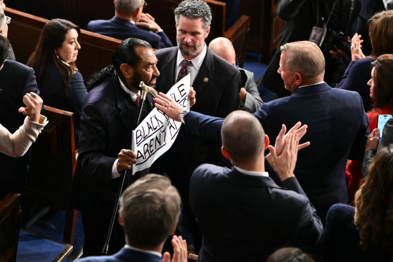 U.S. Rep. Al Green, D-Tx., exits as he holds a sign reading "Black people aren't apes" during President Trump's State of the Union address in the House Chamber of the US Capitol in Washington, DC, on February 24, 2026.