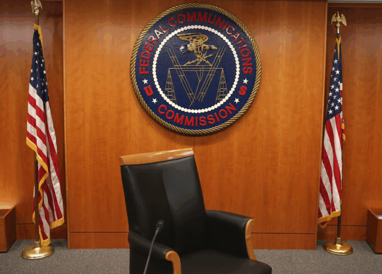 The seal of the Federal Communications Commission hangs between two American flags; the FCC is urging broadcasters to air more "patriotic" content in the run-up to the country's 250th celebrations this summer.