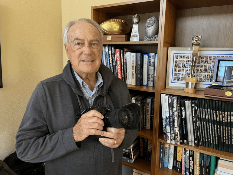 John Biever poses with a camera in front of some memorabilia at his San Diego home.