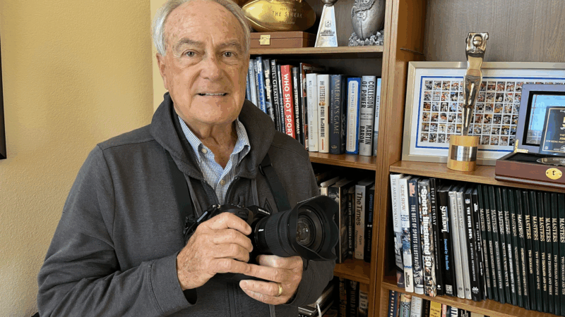 John Biever poses with a camera in front of some memorabilia at his San Diego home.