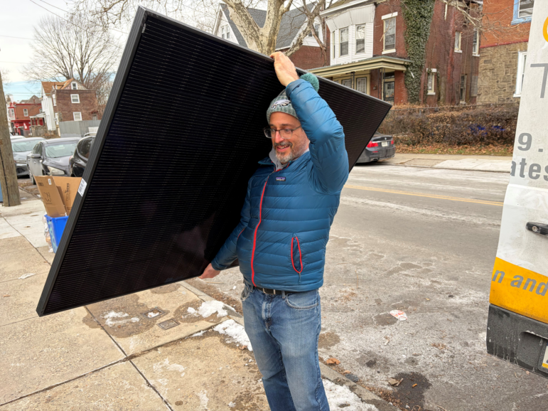Solar States owner Micah Gold-Markel carries a solar panel from a truck to the house where it will be installed.