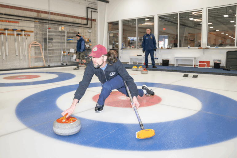 Ted Hallock delivers a rock during a curling game at the Potomac Curling Club in Laurel, Md. Curling clubs often see a boost in interest following the Winter Olympics.