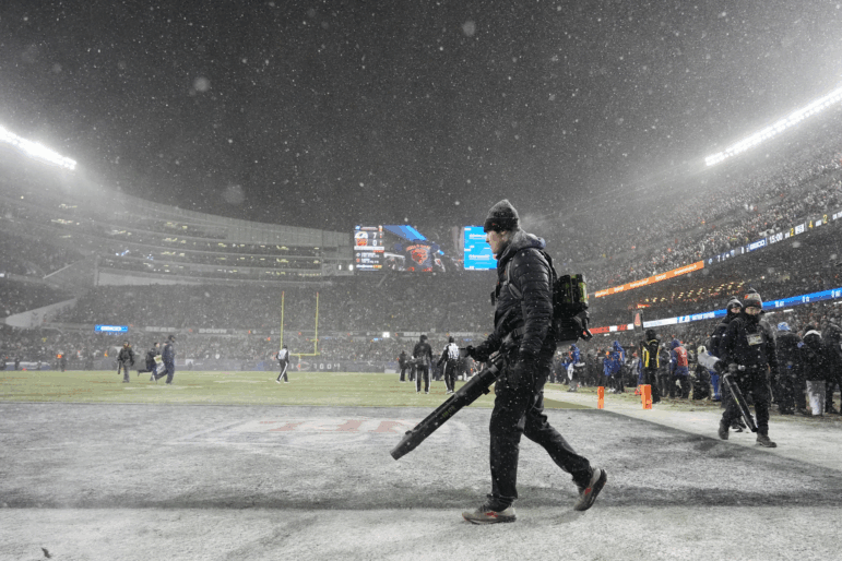 Grounds crew members glow snow off the field at Soldier Field during the first half of an NFL football divisional playoff game between the Chicago Bears and the Los Angeles Rams Sunday, Jan. 18, 2026, in Chicago.