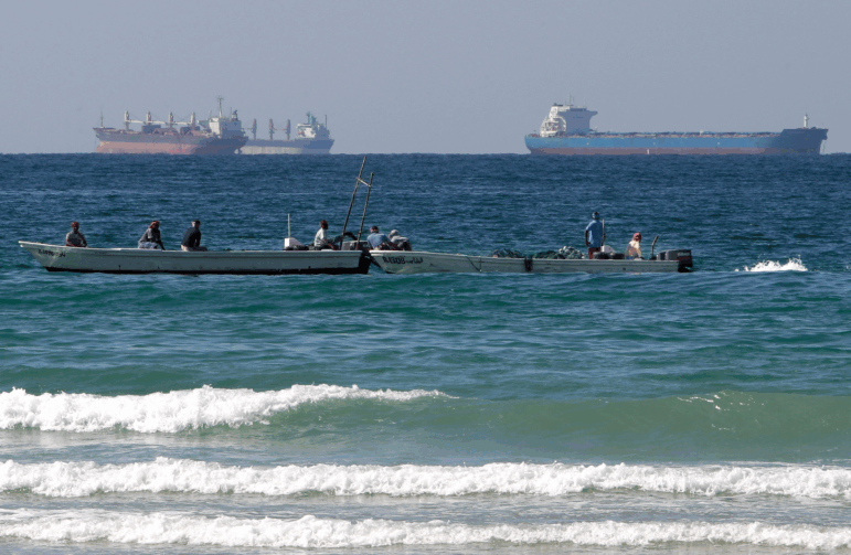 Fishermen work in front of oil tankers south of the Strait of Hormuz on Jan. 19, 2012, offshore of the town of Ras Al Khaimah in United Arab Emirates.