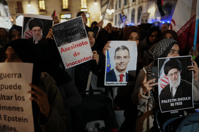 Demonstrators hold photographs of Spain's prime minister and the killed Iranian supreme leader.