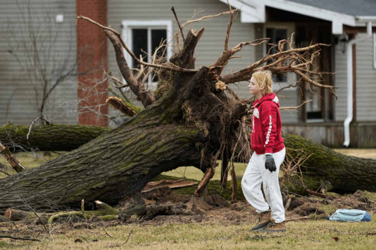 A volunteer works to clear debris a day after a storm whipped up a tornado through the area, in Union City Mich. on Saturday.