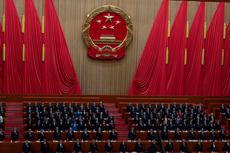 Delegates including Chinese President Xi Jinping (center) stand as the national anthem is sung during the closing session of the National People's Congress at the Great Hall of the People in Beijing, Thursday.