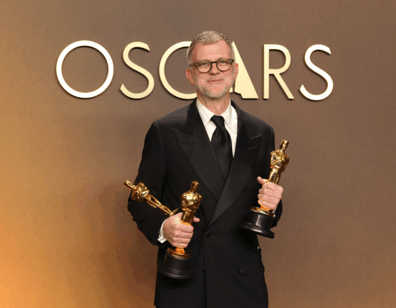 Paul Thomas Anderson holds his Oscars for best adapted screenplay, best director and best picture for One Battle After Another.