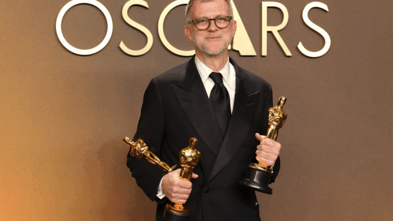 Paul Thomas Anderson holds his Oscars for best adapted screenplay, best director and best picture for One Battle After Another.