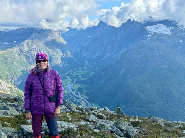 This photo shows Jean Muenchrath standing against a backdrop of mountain peaks.