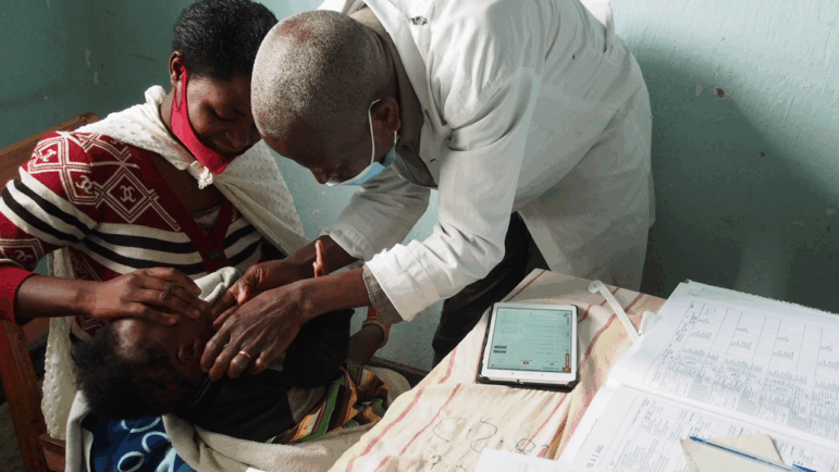 The photo is of a child (held by his mother) who was treated with the ePOCT+ algorithm in a health center in Rusizi district, Rwanda. The photo was taken by Magali Rochat in May 2023.